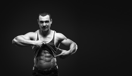 Bodybuilder showing his press. A man shows his abdominal muscles, raised his hand t-shirt. Press, muscles, show, bodybuilding. Sports guy.の写真素材