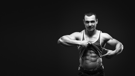 Bodybuilder showing his press. A man shows his abdominal muscles, raised his hand t-shirt. Press, muscles, show, bodybuilding. Sports guy.の写真素材