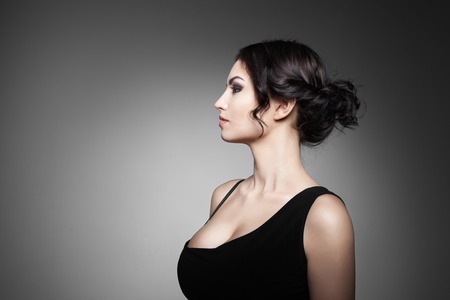 Fashion Brunette Girl. Profile portrait of a beautiful  woman on dark background. Luxury woman. Concept of beauty and fashion.の写真素材