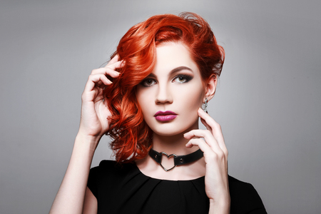 Portrait of beautiful sexy girl with red hair styling and professional makeup. Luxury slender woman.の写真素材