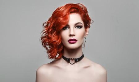 Portrait of beautiful sexy girl with red hair styling and professional makeup. Luxury slender woman.の写真素材
