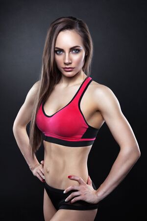 Sexy young woman standing on grey background. Fitness female looking at camera. Concept of sport and healthy lifestyle.の写真素材