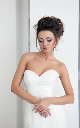 Portrait of young beautiful bride over white background. Make-up and hairstyle for the wedding.の写真素材