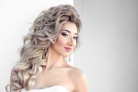 Portrait of young beautiful bride over white background. Make-up and hairstyle for the wedding.の写真素材