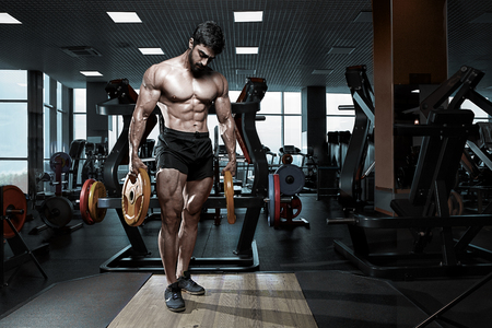 Muscular athletic bodybuilder fitness model posing after exercises in gymの写真素材