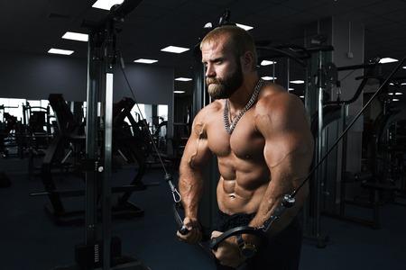 Muscular man working out in gym doing exercises at triceps, strong male naked torso absの写真素材