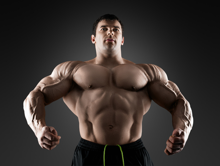 Handsome muscular bodybuilder posing over black background. Concept of the sport, strong, healthy lifestyle and nutrition.の写真素材