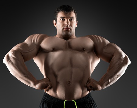 Handsome muscular bodybuilder posing over black background. Concept of the sport, strong, healthy lifestyle and nutrition.の写真素材