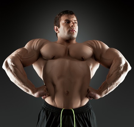 Handsome muscular bodybuilder posing over black background. Concept of the sport, strong, healthy lifestyle and nutrition. Isolated with clipping path.の写真素材