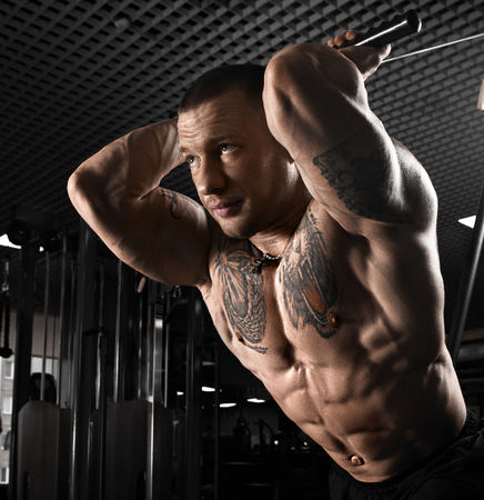 Muscular athletic bodybuilder model posing after exercises in gymの写真素材