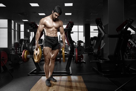 Muscular athletic bodybuilder fitness model posing after exercises in gymの写真素材