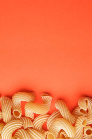 Pasta penne rigate on orange backgroundの写真素材
