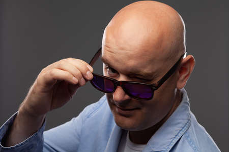 bald man in black glasses on a gray backgroundの写真素材