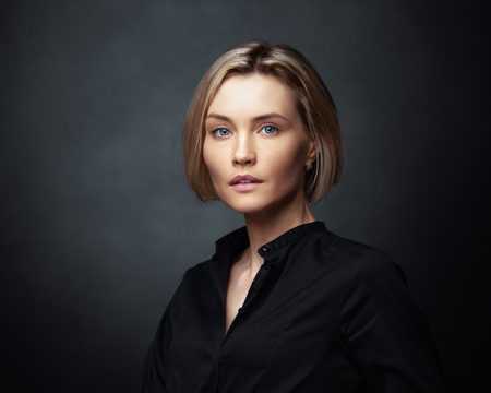 Beautiful middle-aged woman on a gray background in a black blouse.の写真素材