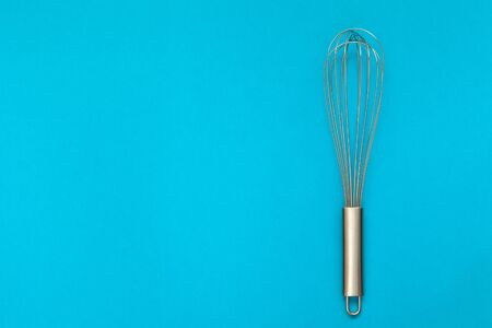 Metal whisk for whipping on a blue background.の写真素材