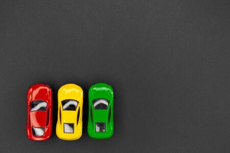 Yellow, green and red toy cars on a gray background, top view.の写真素材