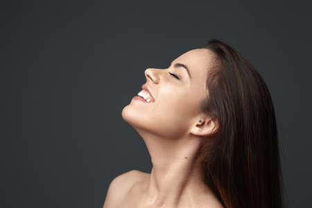 Beautiful young girl smiling on a gray backgroundの写真素材