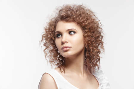 A beautiful young girl with curly hair on gray backgroundの写真素材