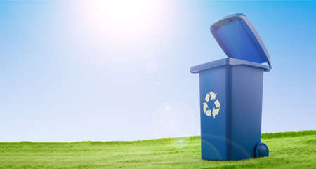 A plastic blue container stands on green grass against blue sky.の写真素材