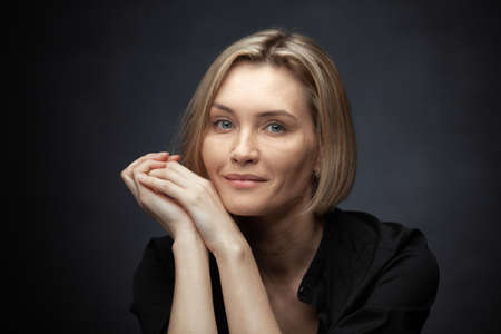 Beautiful middle-aged woman on a gray background in a black blouse.の写真素材