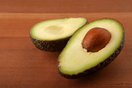 Closeup Avocado cut in half on wooden board backgroundの写真素材