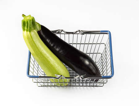 Eggplant and zucchini in the shopping basket. Shopping concept with fresh vegetables on white background.の写真素材