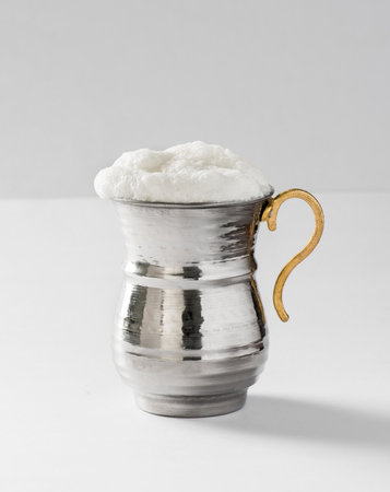 BUTTERMILK. Traditional Turkish yoghurt drink with foam in silver metal cup. Buttermilk.
