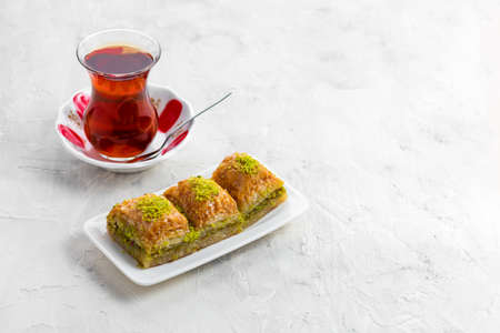 BAKLAVA. Traditional Turkish Desserts Baklava with Turkish Tea. Crispy pistachio baklava on white plate.の写真素材