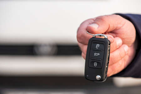 Man hand holding a car key. New car sell, auto showroom, car sale deal concepts. Black car key.