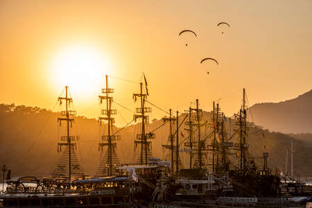 FETHIYE, MUGLA, TURKEY - August 21, 2021: Sunset view on OLUDENIZ, FETHIYE. Paragliding and tour boats on sunset. Very beautiful touristic destination. Oludeniz - Fethiye, Mugla, Turkey.のeditorial素材