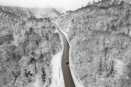 Beautiful winter landscape aerial view. Winter snowy forest with winding mountain road view. Drone...