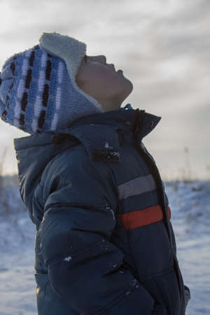 Boy in winter looked up to heaven and looks closelyの写真素材