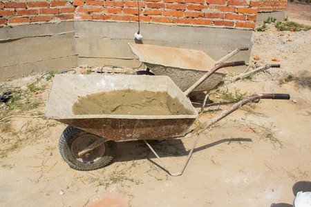 parked empty, dirty metal wheelbarrow for construction