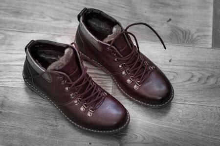 men's winter boots to lace on a wooden floor old blackの写真素材
