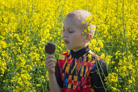 boy with ice cream in rapeseed,boy looks at ice cream in rapeseed field in summer