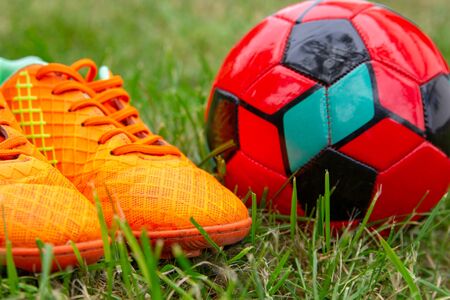 children's soccer shoes with a ball on the grassの写真素材