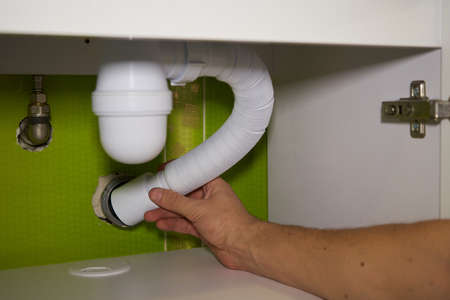 plumbing works under the sink installs a pipe in the sewerの写真素材