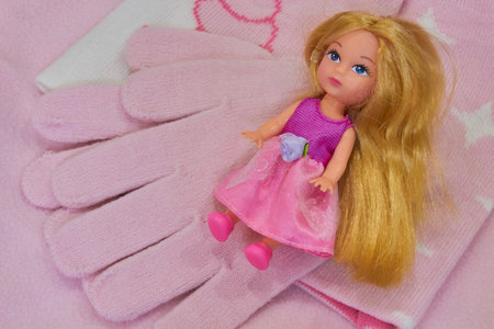 pink gloves with a doll for a little girl, a set of beautiful winter clothes for a childの写真素材