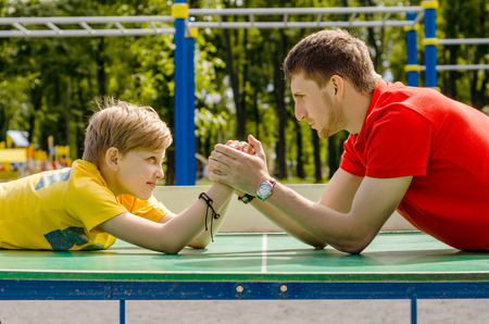 Young man is playing with boy with hands in the park