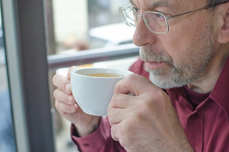 Close up of aged man with a cup of teaの写真素材