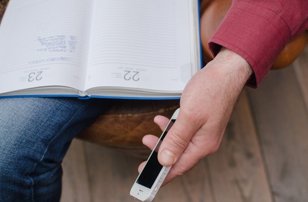 Aged man with day planner uses cellphoneの写真素材
