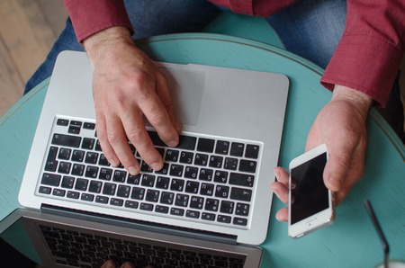 Aged man using his phone and lap top in the cafeの写真素材