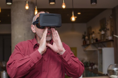 Aged man in the virtual glasses in the cafeの写真素材