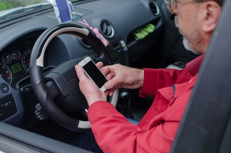 Aged man talking on the phone in the car