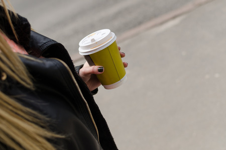 Young woman drinking cofee from the cup in the cityの写真素材