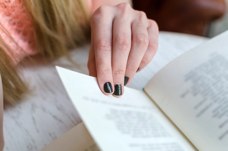 Young girl is sitting with the book in the roomの写真素材