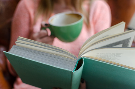 Young girl is sitting with the book in the roomの写真素材