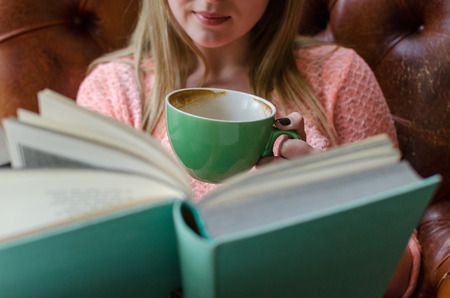 Young girl is sitting with the book in the room