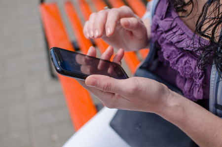 Young girl resting on the bench with her cellphoneの写真素材
