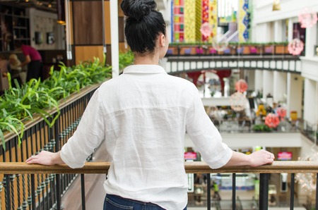 Young woman standing near the fence in the shopping mallの写真素材
